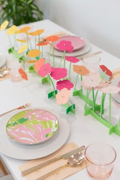 the table is set with paper flowers and place settings