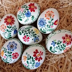 six painted eggs sitting on top of straw