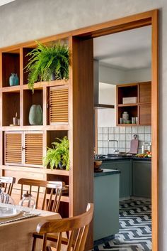 a dining room table and chairs in front of a wooden bookcase with plants on it