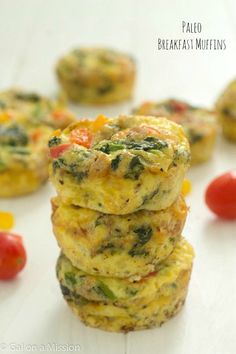 three small muffins stacked on top of each other with tomatoes and spinach in the background