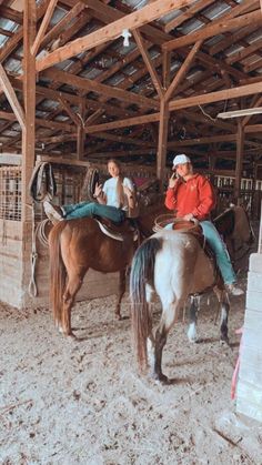 two people are riding horses in an enclosed area