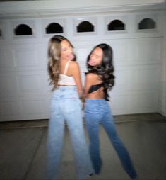 two young women standing next to each other in front of a garage door with their mouths open