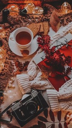 a table topped with a cup of tea next to a camera and other items on top of it