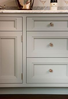 a white kitchen cabinet with two drawers and knobs on the bottom, next to a counter top