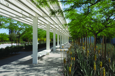 a row of white benches sitting next to each other under a pergolated roof