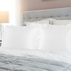 a bed with white sheets and pillows in a bedroom