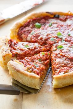 a deep dish pizza on a cutting board with a knife and fork next to it