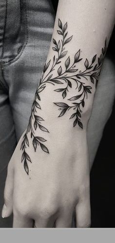 a woman's arm with black leaves on it