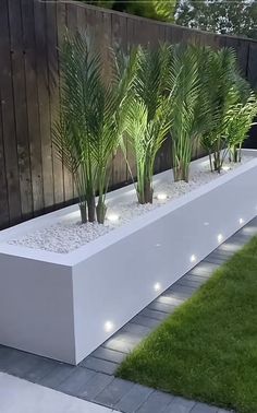 a white planter filled with lots of plants next to a wooden fence and grass