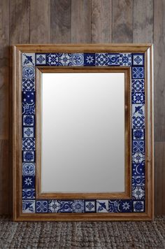 a blue and white tile framed mirror against a wooden wall