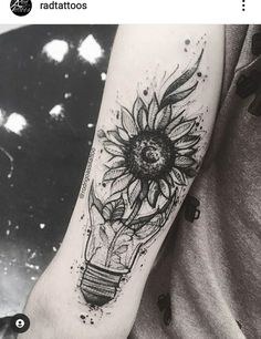 a black and white photo of a sunflower in a light bulb tattoo on the arm