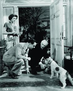 an old black and white photo of three people with two dogs in front of a door