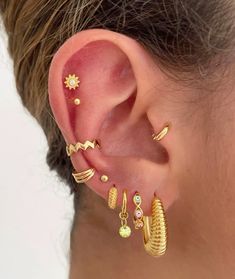 a woman wearing gold ear cuffs and earrings