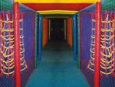 an indoor play area with colorful walls and ropes on the ceiling, along with blue carpeting