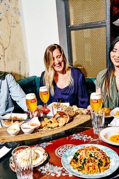 three women sitting at a table with food and drinks