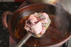 some meat is cooking in a pot on the stove