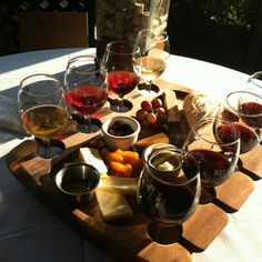 several glasses of wine and cheese on a wooden tray