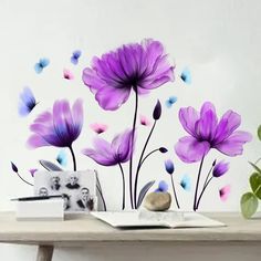 purple flowers and butterflies are painted on the side of a table next to a potted plant