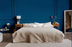 a bedroom with blue walls and white bedding, two nightstands on either side