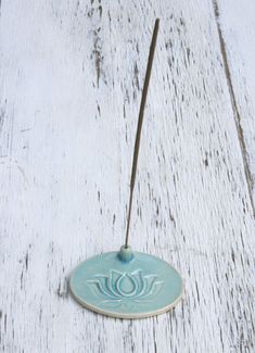 a blue ceramic incense burner sitting on top of a white wooden table next to a string