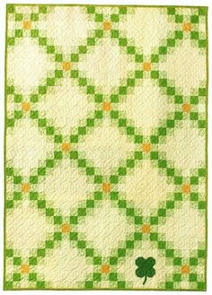 a green and white quilt with an irish shamrock on the center, in front of a white background