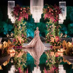 a model walks down the runway in a gown with flowers and chandeliers behind her