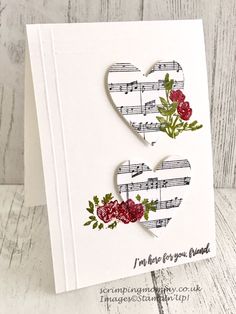 a card with two hearts made out of sheet music and red flowers on the front