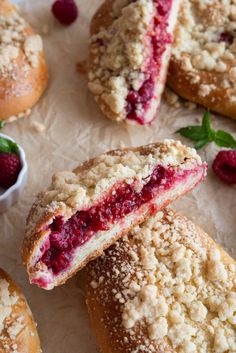 raspberry crumb filled pastries on parchment paper with fresh berries in the background