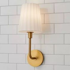 a wall light with a white shade on it's side against a white brick wall