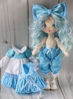 two dolls are sitting next to each other on a wooden surface, one is blue and the other is white