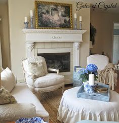 a living room filled with furniture and a fire place covered in candles next to a painting