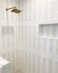 a white tiled bathroom with a shower head