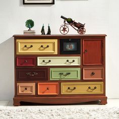 an old dresser with many drawers and pictures on the wall above it is painted in different colors