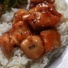 a white plate topped with rice and meat covered in sauce next to broccoli