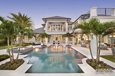 an outdoor pool surrounded by palm trees in front of a house