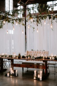 a long wooden table with candles and greenery on the top is set up for a wedding reception