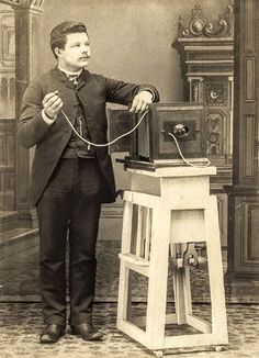 an old photo of a man standing next to a table with a machine on it