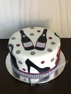 a cake decorated with polka dots and two bottles of wine on top of the cake