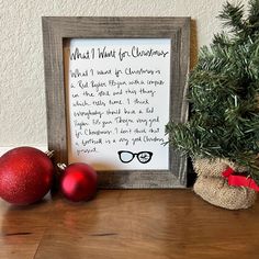 two christmas ornaments sitting on top of a wooden table next to a sign that says what i want for christmas