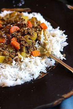 a black plate topped with rice and vegetables