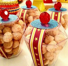 three plastic containers filled with cookies on top of a white tablecloth covered countertop