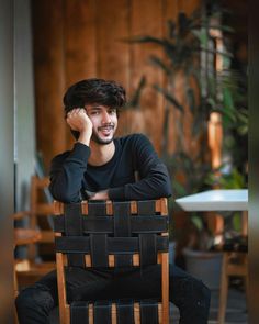 a man sitting in a chair with his hand on his head while talking on the phone