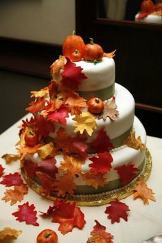 a three tiered cake decorated with leaves and pumpkins