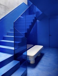 a white bench sitting in front of a set of blue stairs with glass railings