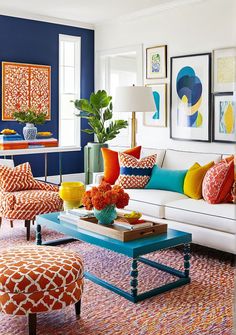 a living room with blue walls, orange and white furniture and pictures on the wall