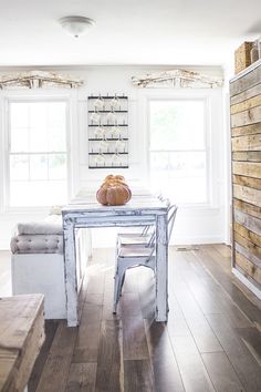 a table with a pumpkin sitting on top of it in front of two large windows