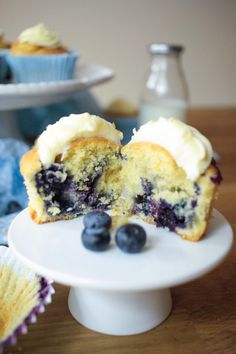 a blueberry muffin is cut in half on a white plate with some blueberries