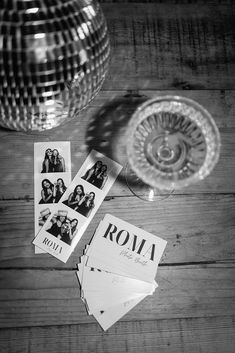 several photographs are laying on the table next to a wine glass and disco ball, which has been placed in front of it