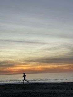 a person running on the beach at sunset