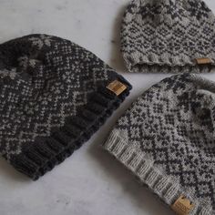 three knitted hats sitting on top of a white counter next to each other,